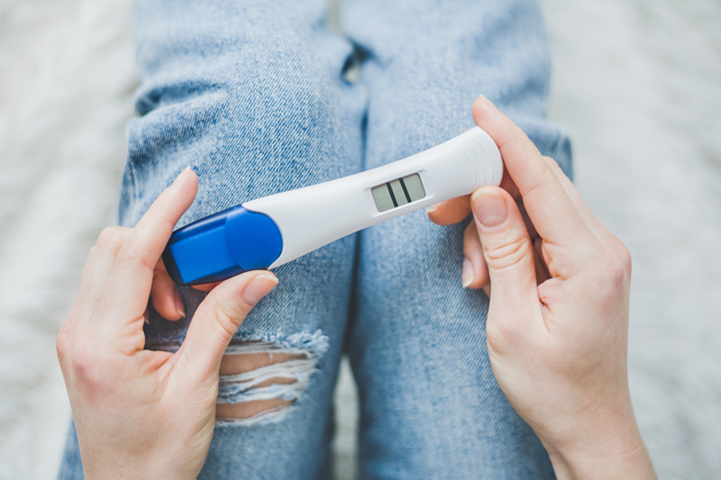 a woman looking at a positive pregnancy test