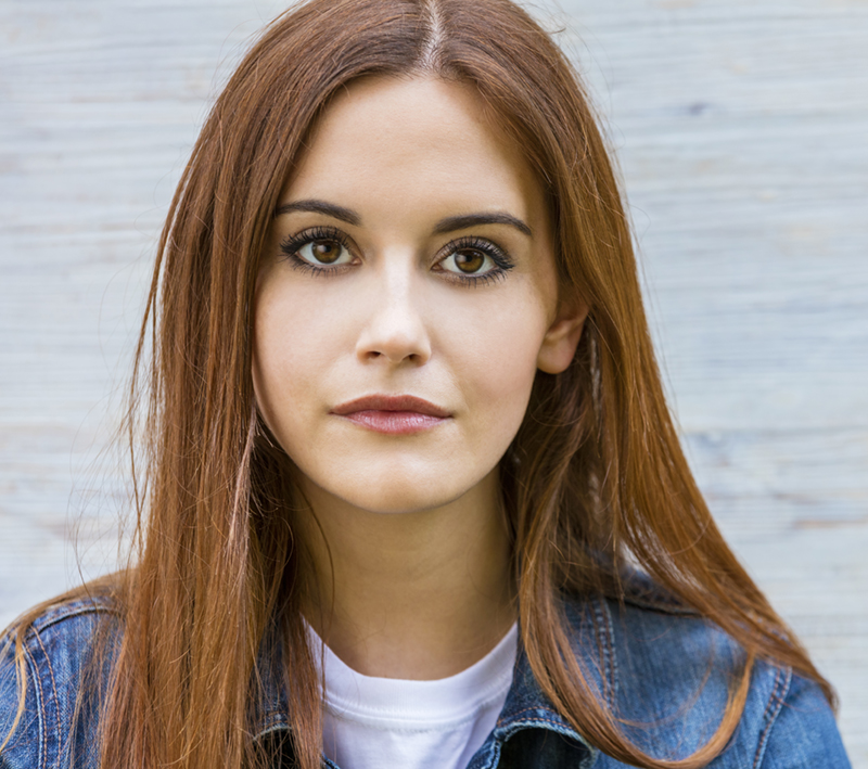 a young brunette woman looking at the camera with a serious look on her face